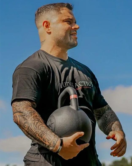 Diogo Souza outdoors, holding a kettlebell, in a Ludus Actius shirt