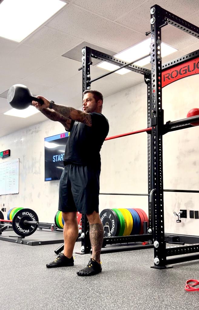 A member swinging a kettlebell in front of the rack at Ludus Actius