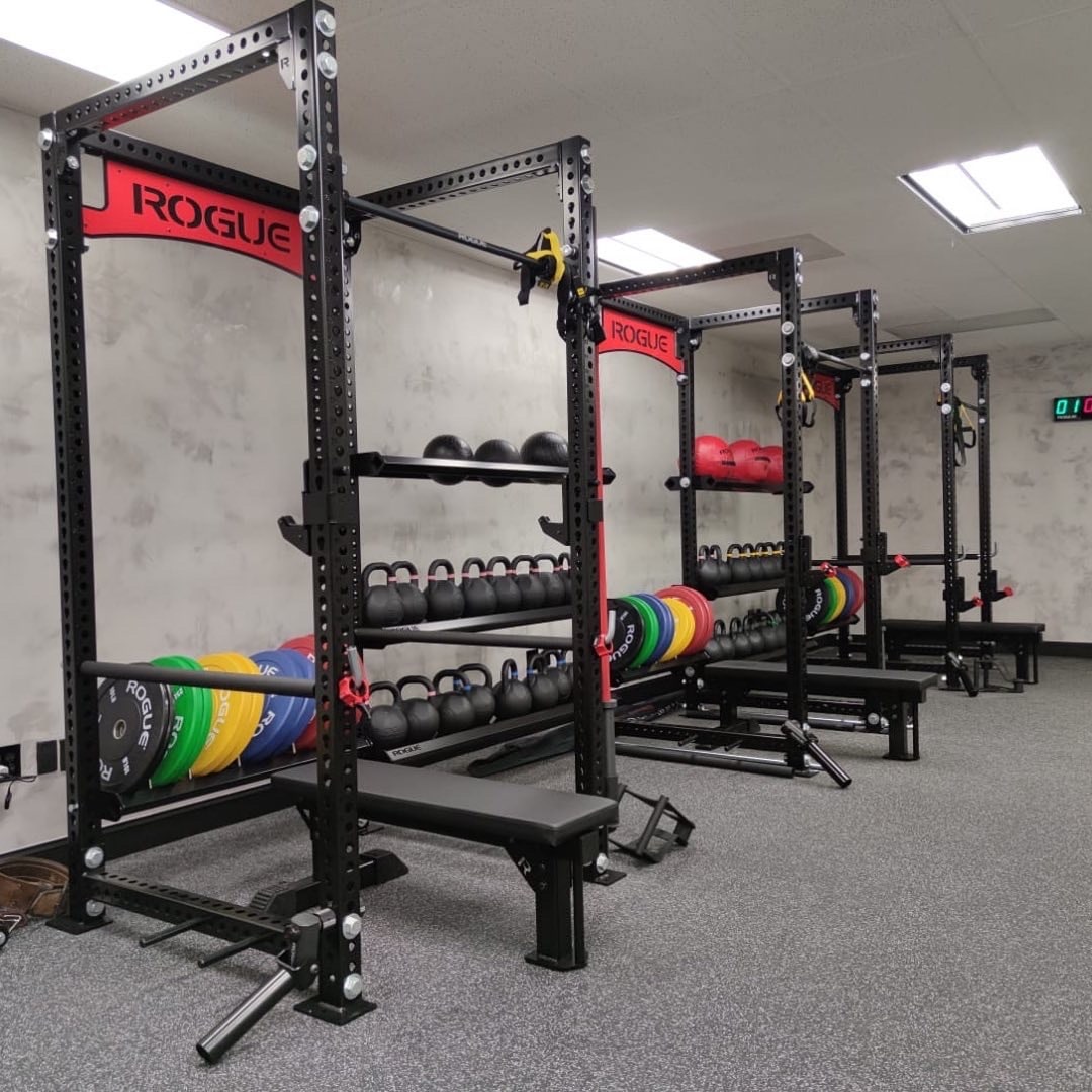 Four squat racks with bumper plates loaded on the uprights